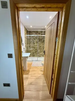 a bathroom with a door leading into a bathroom with a sink at Acorn Lodge Pentewan in St Austell