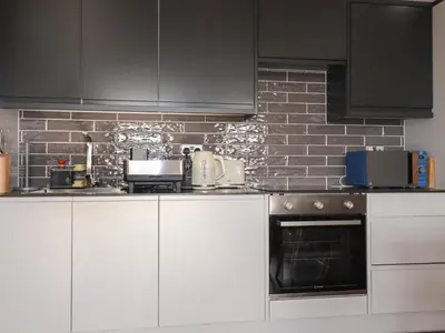 a kitchen with white cabinets and a brick wall at Priory in St Austell