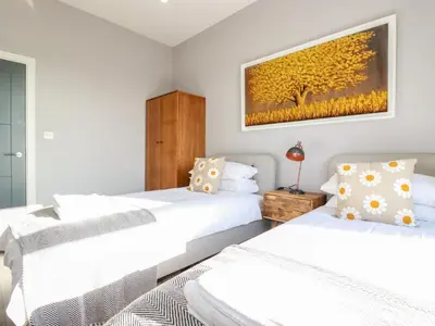 two beds in a bedroom with a painting on the wall at Priory in St Austell