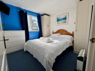 a bedroom with blue walls and a bed with white sheets at 5 Berth Chalet Holiday Apartment in Cornwall in Padstow