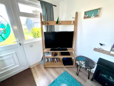 a living room with a television and a book shelf at 5 Berth Chalet Holiday Apartment in Cornwall in Padstow