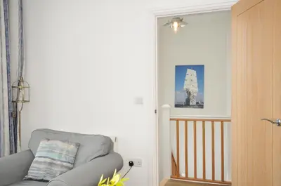 a living room with a gray chair and a staircase at Falmouth Bay 2 in Falmouth