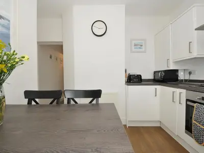 a kitchen with white cabinets and a clock on the wall at Falmouth Bay 2 in Falmouth