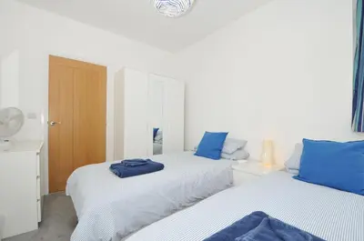 two beds in a white room with blue pillows at Falmouth Bay 2 in Falmouth