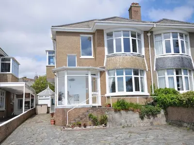 a brick house with white windows on a street at Falmouth Bay 2 in Falmouth