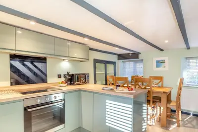 a kitchen and dining room with a table and chairs at Lanreath Cottage with hot tub, The Vale, Cornwall in Looe