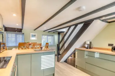 a kitchen with blue cabinets and a staircase at Lanreath Cottage with hot tub, The Vale, Cornwall in Looe