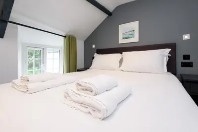 a bedroom with a large white bed with towels on it at Lanreath Cottage with hot tub, The Vale, Cornwall in Looe