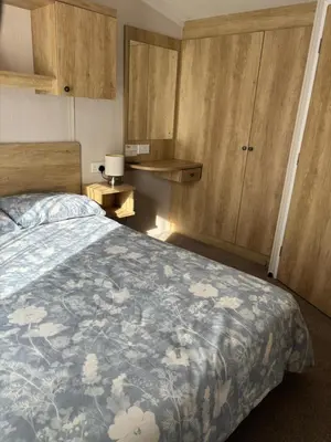a bedroom with a bed and wooden cabinets at Two bedroom Holiday Home with countryside view in St Austell