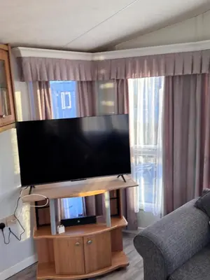 a flat screen tv on a wooden stand in a living room at Sunset Serenity in Perranporth