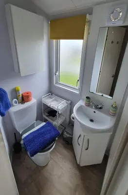 a bathroom with a sink and a toilet and a mirror at HolidayLet 24 Bude Newperran Holiday Park in Cubert