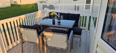 a balcony with a table and chairs on a deck at HolidayLet 24 Bude Newperran Holiday Park in Cubert