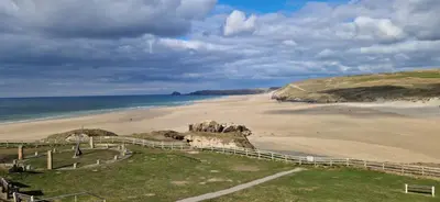 a sandy beach with a fence and the ocean at HolidayLet 24 Bude Newperran Holiday Park in Cubert