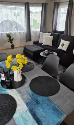 a living room with a couch and a table with yellow flowers at HolidayLet 24 Bude Newperran Holiday Park in Cubert