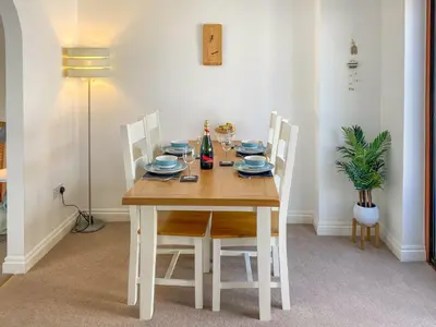 a dining room table with white chairs and a wooden table with plates at Chy An Mordros in Hayle