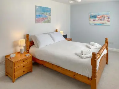 a bedroom with a wooden bed with white sheets and pillows at Chy An Mordros in Hayle