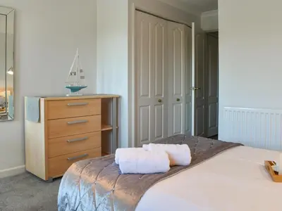 a bedroom with a large bed and a dresser at Camelside in Wadebridge