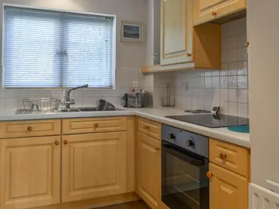 a kitchen with wooden cabinets and a sink and a window at Camelside in Wadebridge