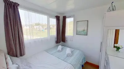 a small bedroom with a bed and two windows at D48 Sunvale, Riviere Towans in Hayle