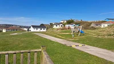 a park with a playground on a hill with houses at D48 Sunvale, Riviere Towans in Hayle