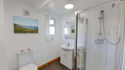 a white bathroom with a shower and a sink at D48 Sunvale, Riviere Towans in Hayle