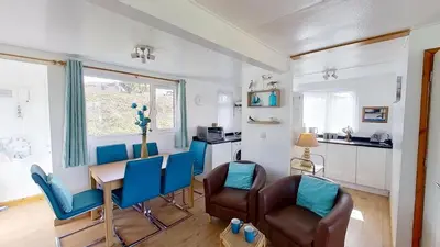 a living room with a table and chairs and a kitchen at D48 Sunvale, Riviere Towans in Hayle