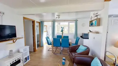 a living room with a table and blue chairs at D48 Sunvale, Riviere Towans in Hayle