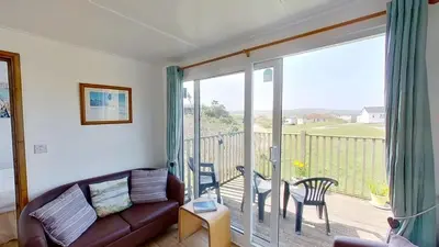 a living room with a couch and a balcony at D48 Sunvale, Riviere Towans in Hayle