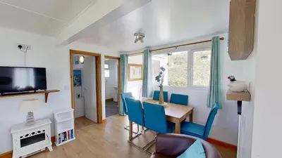 a living room with a table and chairs and a television at D48 Sunvale, Riviere Towans in Hayle