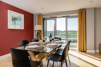 a dining room with a table and chairs and a large window at 14 Azure in Fistral, Newquay in Newquay