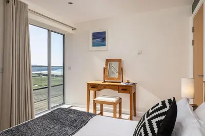 a bedroom with a bed and a desk with a mirror at 14 Azure in Fistral, Newquay in Newquay