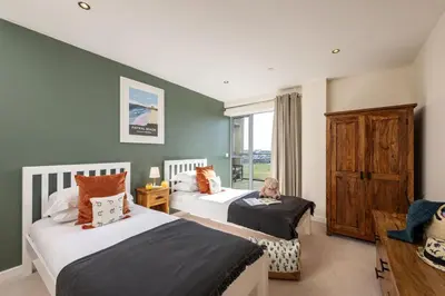 a bedroom with two beds and a child sitting on the bed at 14 Azure in Fistral, Newquay in Newquay