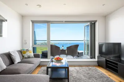 a living room with a couch and a large window at 32 One Lusty Glaze in Newquay in Newquay