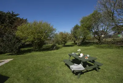 a picnic table sitting in the grass in a field at Ivy Chimney Cottage near Scorrier and close to Porthtowan in Porthtowan