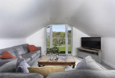 a living room with a couch and a tv at Ivy Chimney Cottage near Scorrier and close to Porthtowan in Porthtowan