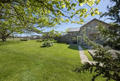 a stone cottage with a picnic table in the yard at Ivy Chimney Cottage near Scorrier and close to Porthtowan in Porthtowan