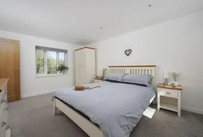 a white bedroom with a large bed and a window at Ivy Chimney Cottage near Scorrier and close to Porthtowan in Porthtowan