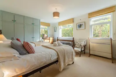 a large bedroom with two beds and a chair at Schoopers - Holiday Home in Rock in Padstow