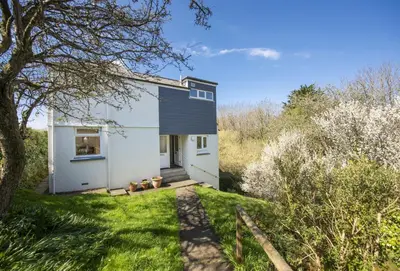 a small white house with a black roof at Schoopers - Holiday Home in Rock in Padstow