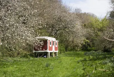 a small red train car sitting in a field at Schoopers - Holiday Home in Rock in Padstow