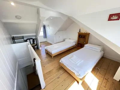 a attic bedroom with two beds and a staircase at Sea Pebble a characterful fisherman cottage in St Ives