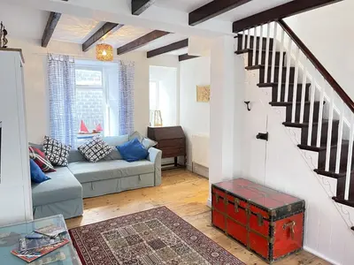 a living room with a couch and a stair case at Sea Pebble a characterful fisherman cottage in St Ives