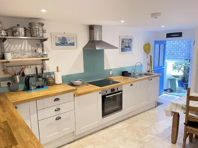 a kitchen with white cabinets and a stove top oven at Sea Pebble a characterful fisherman cottage in St Ives