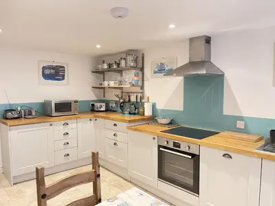 a kitchen with white cabinets and a stove top oven at Sea Pebble a characterful fisherman cottage in St Ives