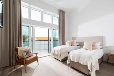 a hotel room with two beds and a chair at 26 Cliff Edge Penthouse in Newquay in Newquay