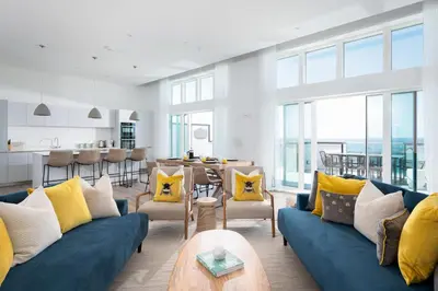 a living room with a blue couch and yellow pillows at 26 Cliff Edge Penthouse in Newquay in Newquay