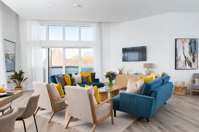 a living room with blue furniture and yellow pillows at 26 Cliff Edge Penthouse in Newquay in Newquay