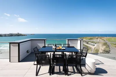 a table and chairs on a balcony with the ocean at 26 Cliff Edge Penthouse in Newquay in Newquay