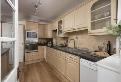 a kitchen with wooden cabinets and white appliances at 3 Menague in Padstow