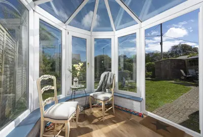 a conservatory with windows and two chairs and a table at 3 Menague in Padstow